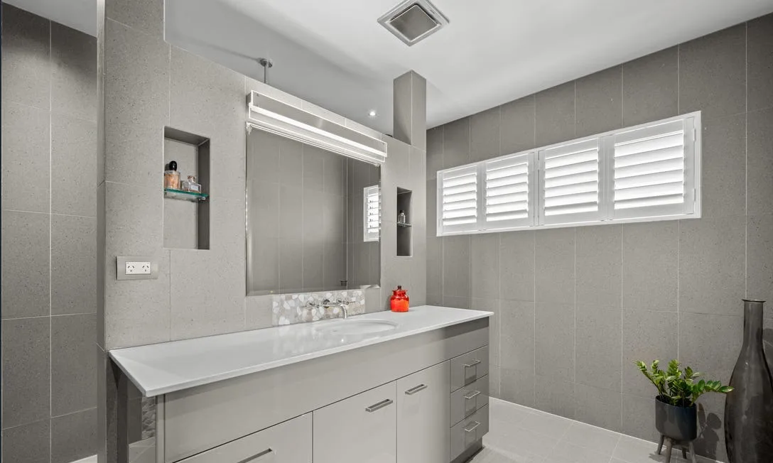 Grey-tiled bathroom with wide vanity and shutters